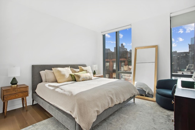 bedroom featuring a wall of windows, a city view, and wood finished floors