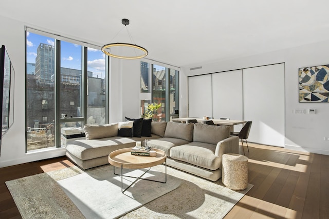 living room with a wall of windows, wood finished floors, visible vents, and a city view