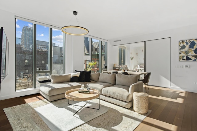 living room with a wall of windows, wood finished floors, visible vents, and a city view