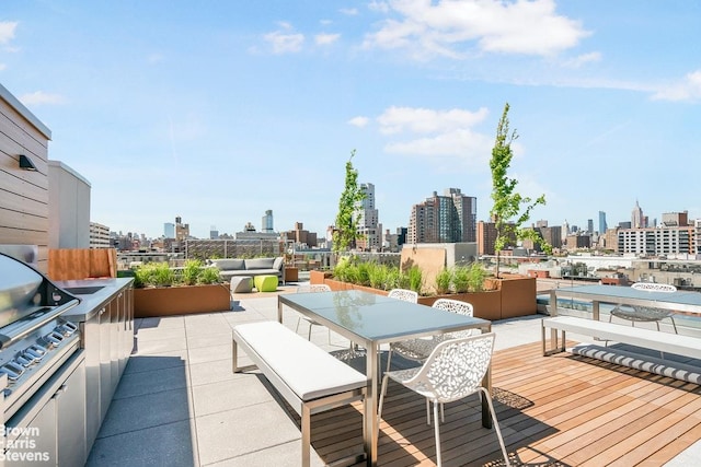 deck featuring a view of city, outdoor dining space, and exterior kitchen