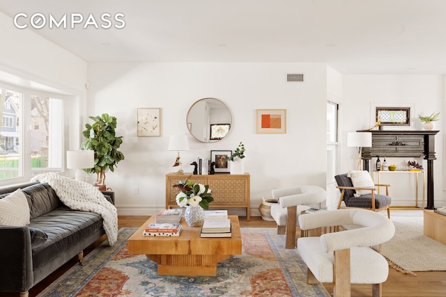 living area with baseboards, visible vents, and wood finished floors