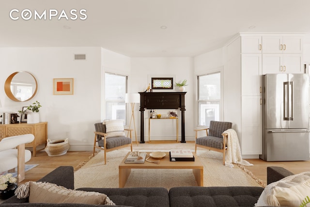 living room featuring baseboards, visible vents, and light wood-style flooring