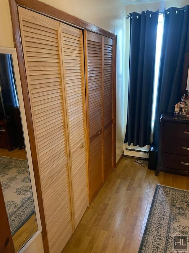 bedroom featuring light wood-style floors, a closet, and a baseboard radiator