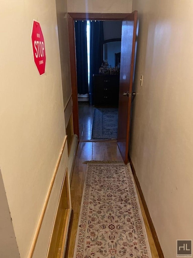 hall with wood finished floors, baseboards, and a baseboard radiator