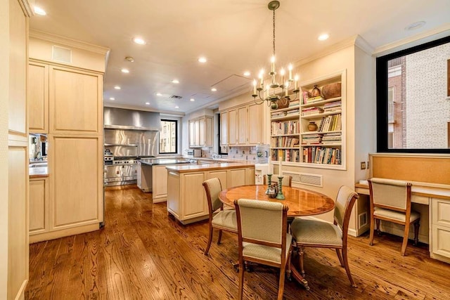 kitchen with wall chimney exhaust hood, hanging light fixtures, light wood-type flooring, ornamental molding, and a kitchen island