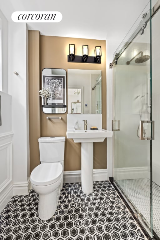 bathroom with toilet, an enclosed shower, and tile patterned flooring