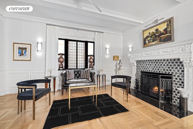 sitting room with parquet floors, ornamental molding, beam ceiling, and a tile fireplace