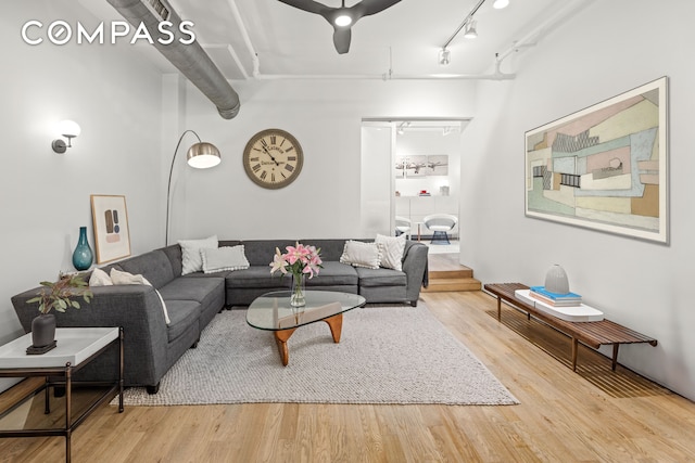 living room featuring track lighting, ceiling fan, and wood finished floors