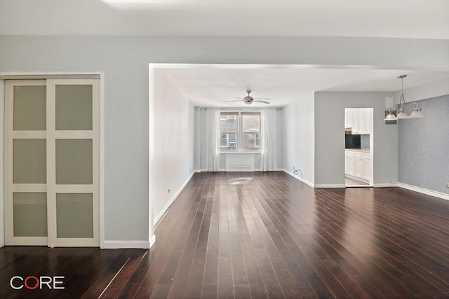 unfurnished living room featuring dark hardwood / wood-style floors and ceiling fan with notable chandelier