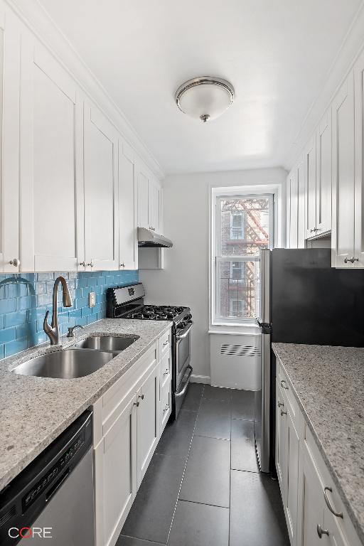 kitchen with sink, white cabinets, backsplash, stainless steel appliances, and light stone countertops