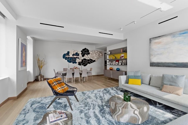 living room with baseboards, wood finished floors, and rail lighting