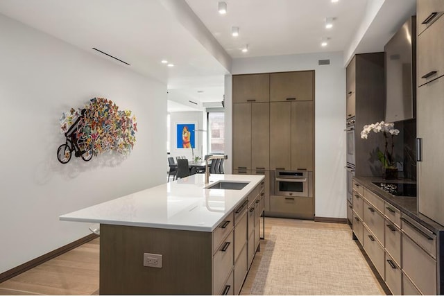 kitchen featuring a large island, sink, black electric cooktop, and light hardwood / wood-style flooring