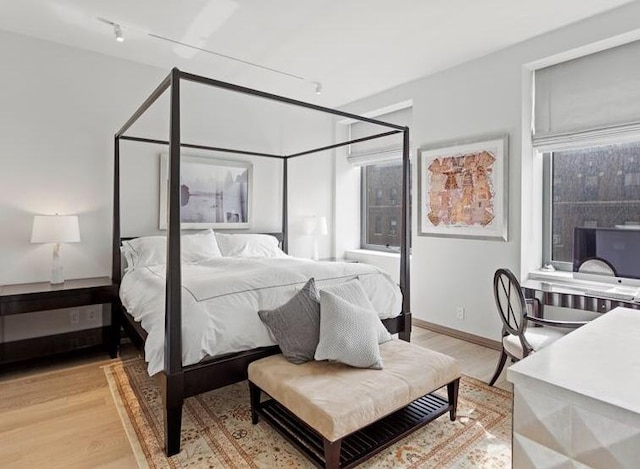 bedroom with rail lighting and light hardwood / wood-style floors