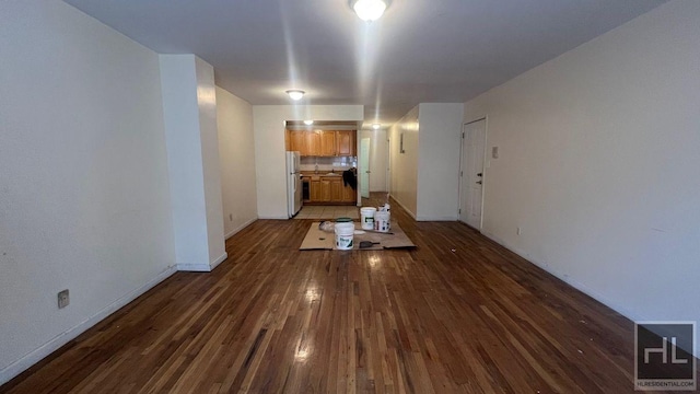 unfurnished living room with a sink, dark wood finished floors, and baseboards