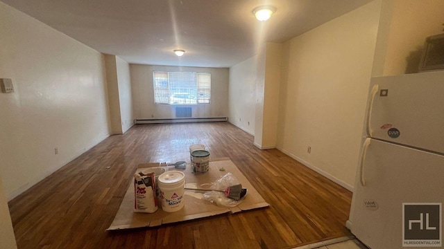 unfurnished living room featuring a baseboard heating unit, baseboards, and wood finished floors