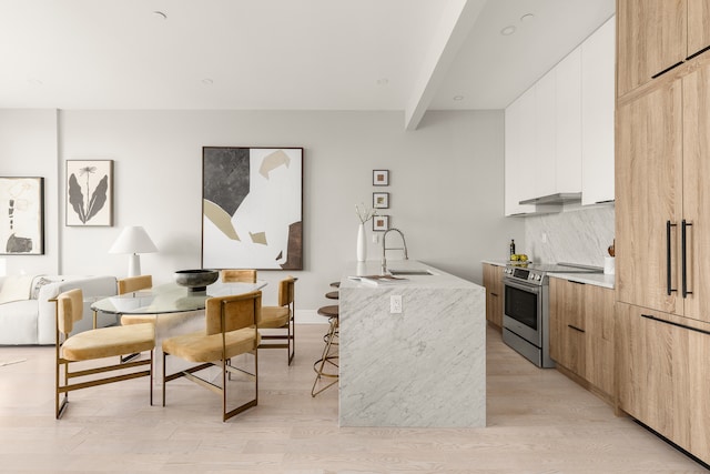 kitchen with electric range, a breakfast bar, a sink, light wood-type flooring, and modern cabinets