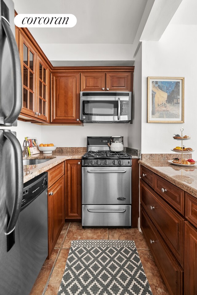 kitchen with light stone counters, appliances with stainless steel finishes, sink, and light tile patterned floors