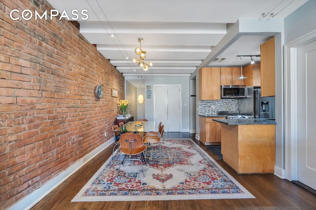 kitchen with appliances with stainless steel finishes, dark hardwood / wood-style floors, hanging light fixtures, and backsplash