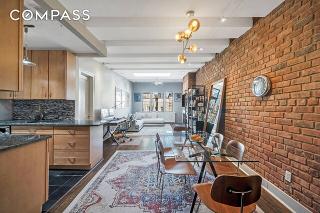 dining area featuring dark hardwood / wood-style floors, brick wall, beam ceiling, and sink