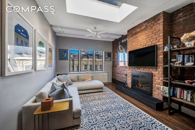 living room featuring dark wood-type flooring, a healthy amount of sunlight, and a brick fireplace