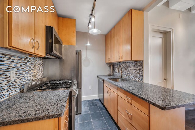 kitchen with backsplash, appliances with stainless steel finishes, sink, and dark stone countertops