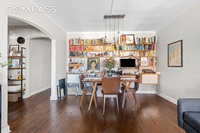 dining room with dark wood-style floors, arched walkways, ornamental molding, and baseboards