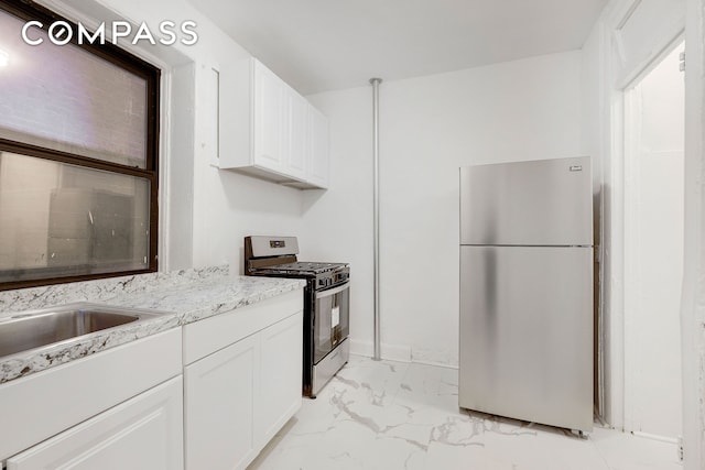 kitchen with white cabinetry, light stone countertops, marble finish floor, and appliances with stainless steel finishes