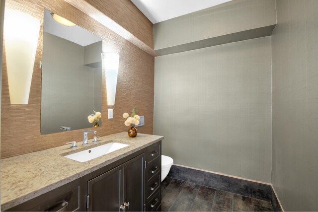 bathroom featuring vanity, hardwood / wood-style floors, decorative backsplash, and toilet