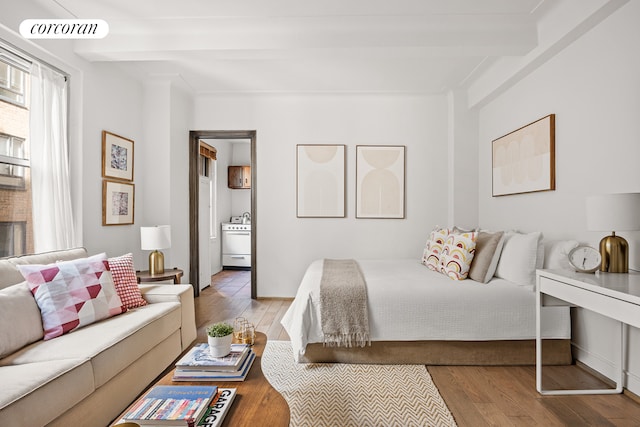 bedroom with ensuite bathroom, hardwood / wood-style floors, beamed ceiling, and visible vents