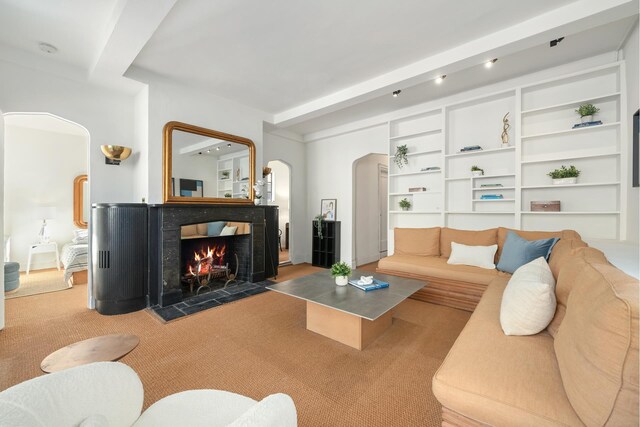 carpeted living room with beamed ceiling and a multi sided fireplace