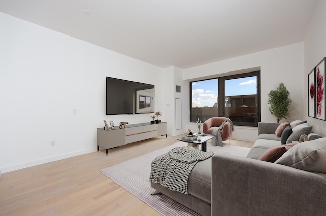 living room with visible vents, baseboards, and light wood-type flooring