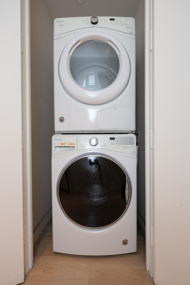 washroom with light wood-type flooring and stacked washer / drying machine