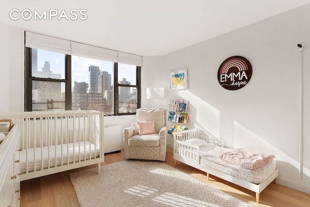 bedroom featuring hardwood / wood-style flooring and a crib