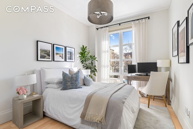 bedroom featuring baseboards, wood finished floors, and ornamental molding