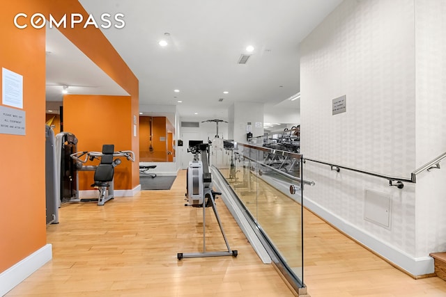 exercise room with wallpapered walls, recessed lighting, wood finished floors, and baseboards