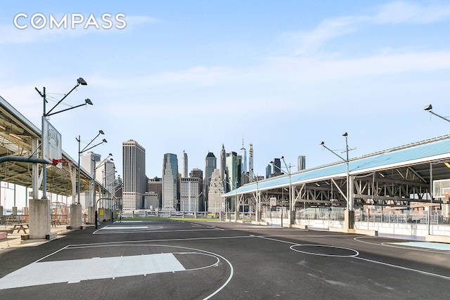 view of sport court with community basketball court, a view of city, and fence