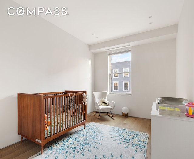 bedroom with a crib and wood finished floors