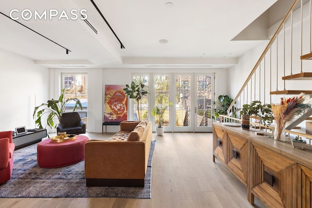 living area featuring a wealth of natural light, stairway, and light wood finished floors