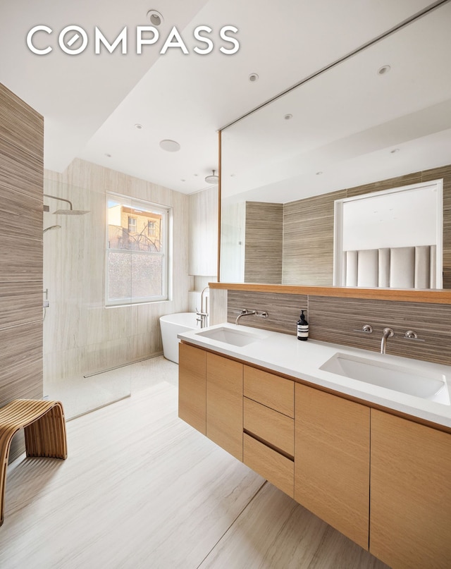 full bath featuring a sink, a soaking tub, walk in shower, and double vanity