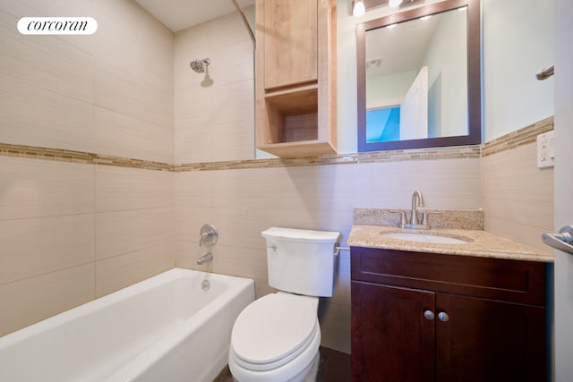 full bathroom with tiled shower / bath combo, vanity, tile walls, and toilet