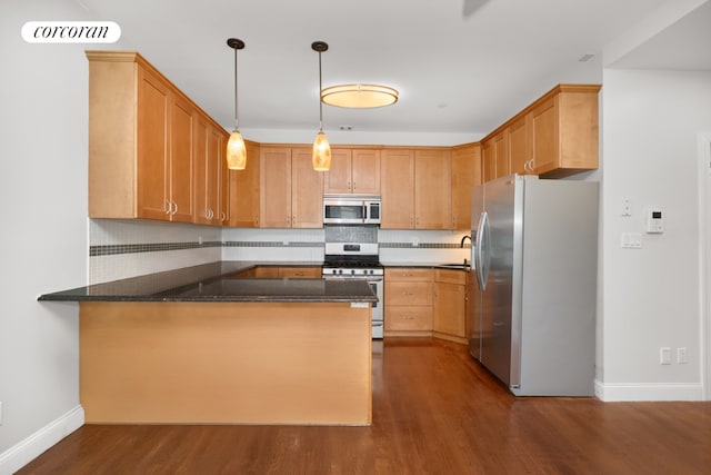 kitchen featuring dark wood-type flooring, sink, kitchen peninsula, pendant lighting, and stainless steel appliances