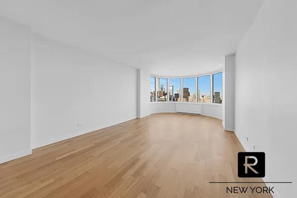 unfurnished living room with light wood finished floors and a view of city