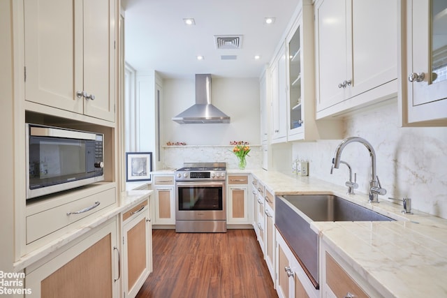 kitchen with visible vents, dark wood-style floors, wall chimney exhaust hood, appliances with stainless steel finishes, and backsplash