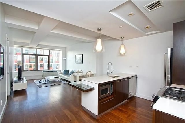 2-17 51st Ave Unit 902, New York City, NY 11101 - kitchen featuring a sink, dark wood-type flooring, a peninsula, appliances with stainless steel finishes, and beamed ceiling