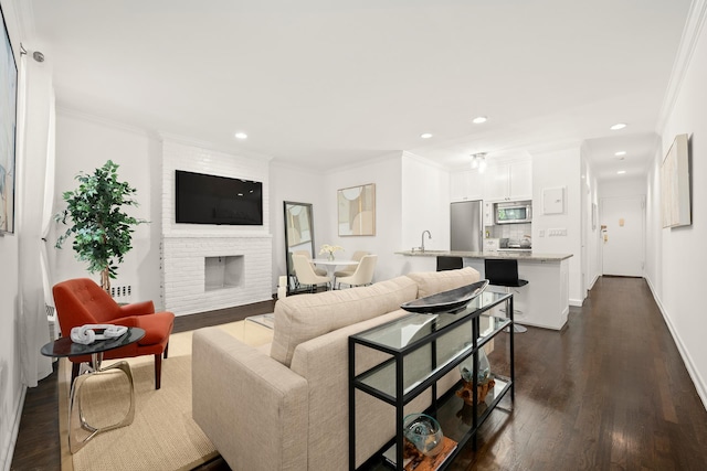 living room with dark wood-type flooring, recessed lighting, crown molding, and a fireplace