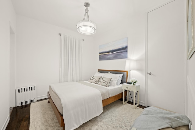 bedroom featuring radiator, wood finished floors, and baseboards