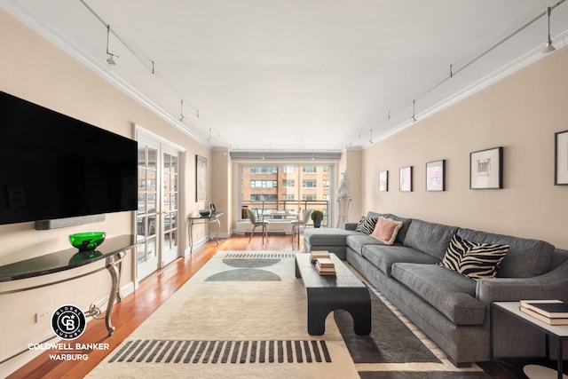 living room with rail lighting, crown molding, french doors, and wood finished floors