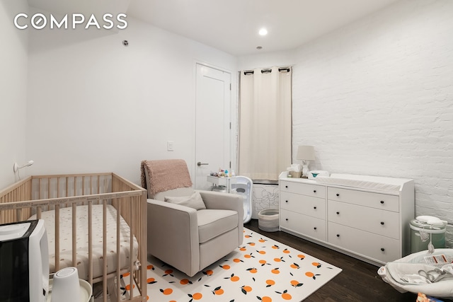 bedroom featuring a nursery area and wood finished floors