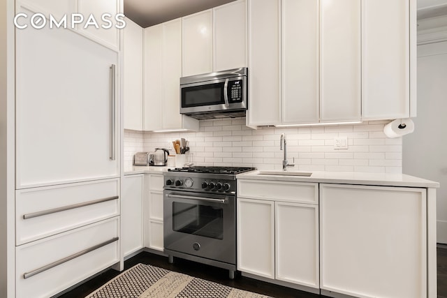 kitchen with stainless steel appliances, a sink, light countertops, and white cabinetry