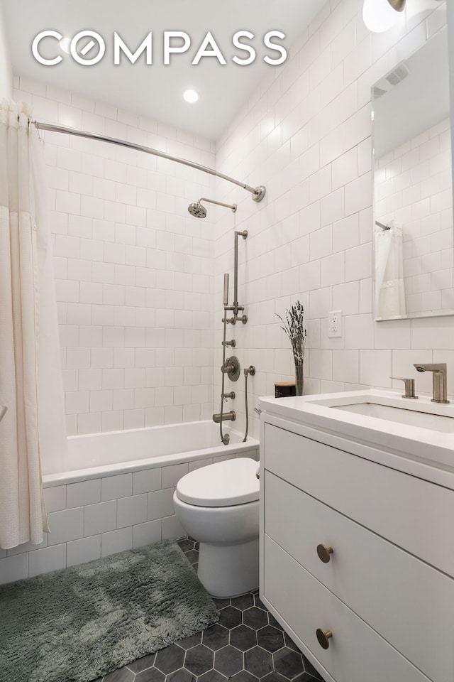 bathroom featuring tiled shower / bath, tile patterned floors, tile walls, toilet, and vanity